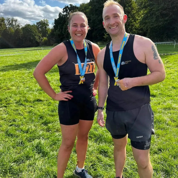 Two gym members looking happy wearing medals for completing a long distance run